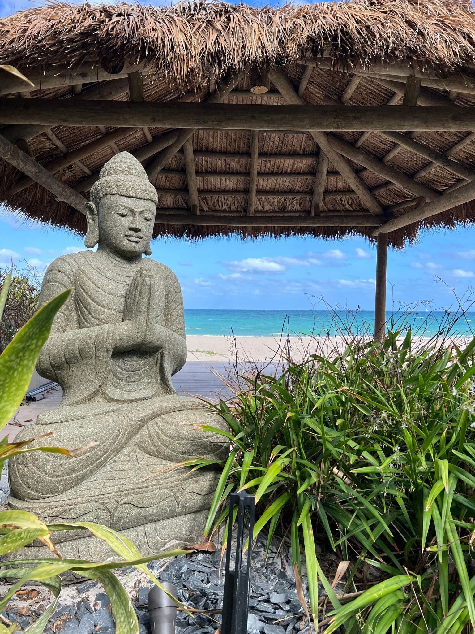 Tiki on a beach over sand with a statue in the foreground